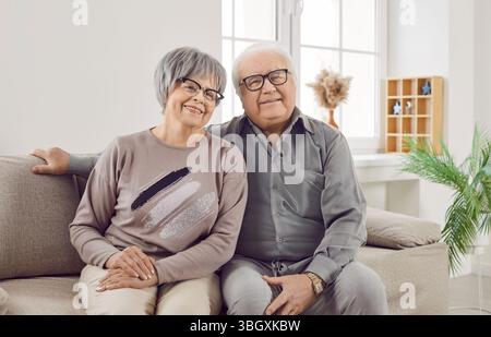 Glückliches Ehepaar der älteren Familie, Frau und Mann, die zu Hause auf dem Sofa im Wohnzimmer sitzen. Stockfoto