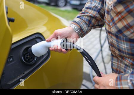 Ladegerät für Elektrofahrzeuge mit Handsteckern, saubere Energie und umweltfreundliches Transportkonzept. Stockfoto