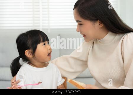 Gemeinsame Aktivitäten während der Feiertage. Eltern und Kinder essen zusammen, Mutter bereitet das Frühstück für die Tochter am Morgen vor, genießen Sie, kleine Stockfoto