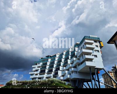 Modernes architektonisches Gebäude unter einem dramatischen bewölkten Himmel. Lido Di Jesolo, Italien Stockfoto
