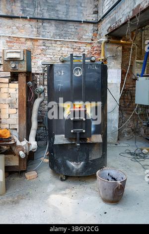 Innenraum der Murano-Glasfabrik mit einem zum Schmelzen von Glas verwendeten Schmelzofen. Umgeben von Industrieanlagen und historischem Mauerwerk Stockfoto