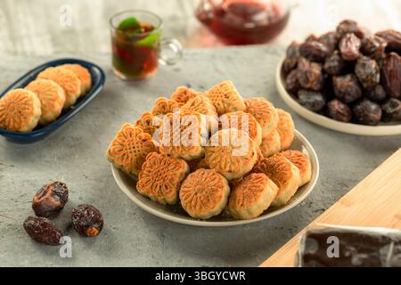 Dattelmaamoul mit Ghee, serviert mit einem Teller Datteln, heller Hintergrund. Stockfoto