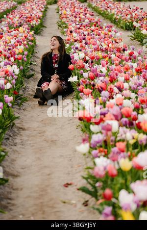 Frau, die zwischen den Reihen blühender Tulpen lacht Stockfoto