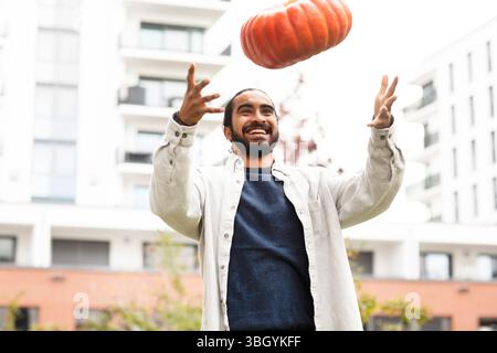 Junger Mann, der einen Kürbis in die Stadt wirft Stockfoto