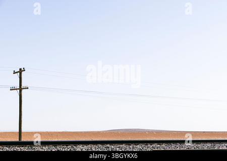 Eisenbahnlandschaft in der ländlichen Wüste mit Telegrafenmast Stockfoto