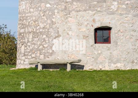 Alte Holzbank vor einer mittelalterlichen Steinwindmühle Stockfoto