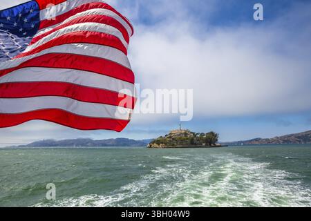 Alcatraz-Insel in der Bucht von San Francisco Skyline, Kalifornien, USA. Meerblick vom Boot nach Alcatraz mit amerikanische Flagge winken. Freiheit und Reisen Stockfoto