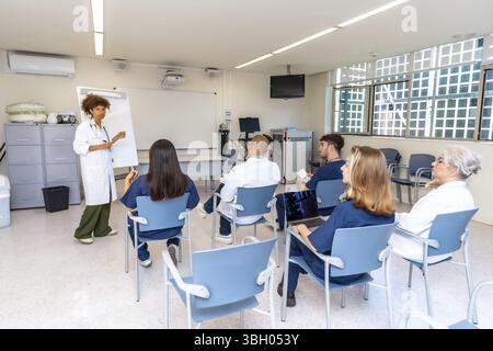 Verschiedene medizinische Fachkräfte, die an einer Präsentation einer Ärztin in einem modernen Besprechungsraum des Krankenhauses teilnehmen Stockfoto