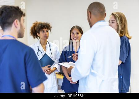 Verschiedene medizinische Fachkräfte arbeiten zusammen, tauschen Fachwissen aus und prüfen Patientendaten während einer produktiven Besprechung im Krankenhaus Stockfoto