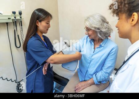 Krankenschwester mit Sphygmomanometer, Blutdruckmessung bei älteren Frauen während der medizinischen Beratung im Krankenhaus oder in der Privatklinik Stockfoto