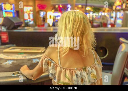 Kaukasische blonde Frau spielen im Casino bei Blackjack Tisch sitzen. Spieler süchtiger Konzept. Lifestyle Mädchen spielen im Casino in Las Vegas, Nevada, Einheit Stockfoto