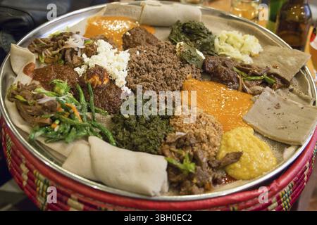 Traditionelle Äthiopische Küche, mehrere Arten von Eintopf und Fleisch auf Injera serviert Stockfoto