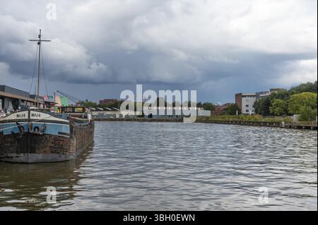 Anderlecht, Hauptstadt Brüssel, Belgien, 13. SEP 2024 - Kanal- und Industrietätigkeit an den Ufern mit regnerischen Wolken, Europa Stockfoto