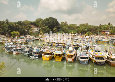 Ganz in der Nähe des Tangalle Harbor an der Südküste Sri Lankas, eine Mischung aus Fischerbooten, Katamaranen und kleinen Motorschiffen, die in ruhigem Türkis vor Anker liegen Stockfoto