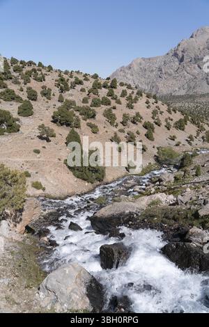 Die schöne Bergwanderstraße mit klarem blauen Himmel und felsigen Hügeln und frischen Bergbach in den Fann Bergen in Tadschikistan Stockfoto