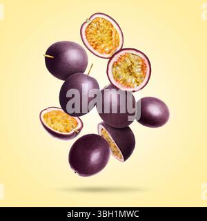 Köstliche reife Passionsfrüchte, die auf blassgelbem Farbverlauf fallen Stockfoto