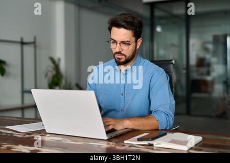 Geschäftiger Geschäftsmann mit Laptop, der im Büro arbeitet. Stockfoto