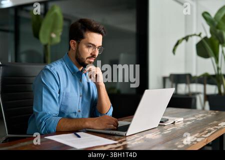 Geschäftiger Geschäftsmann, der über Online-Investitionen nachdenkt und an Notebooks arbeitet. Stockfoto