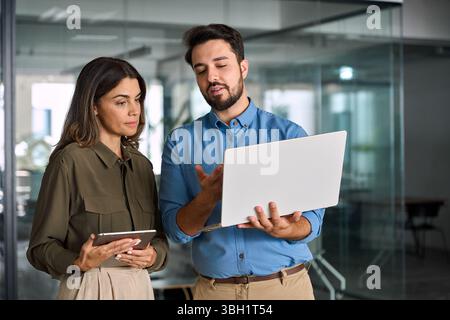 Geschäftlich beschäftigte Geschäftsleute, die im Büro mit Laptop arbeiten und sich unterhalten. Stockfoto