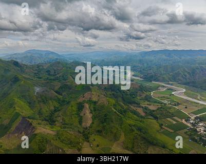 Ackerland und Berge mit grünem Wald. Felder und Flüsse über den tropischen Bergen. Mindanao, Philippinen. Stockfoto