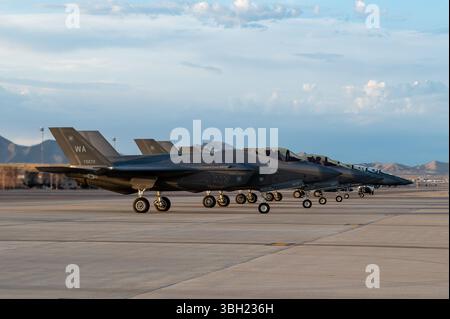 Vier F-35A Lightning IIS und zwei F-15E Strike Eagles warten auf den Start während der U.S. Air Force Weapons School Integration (WSINT) auf der Nellis Air Force Base, Nevada, am 5. Juni 2025. WSINT dient als Höhepunkt für Schüler der U.S. Air Force Weapons School, die Luft-, Raumfahrt- und Cyber-Kräfte in realistischen, missionskritischen Trainingsszenarien zusammenführen, die die Komplexität moderner Kriegsführung widerspiegeln. Die zweimal jährlich stattfindende Integrationsveranstaltung testet domänenübergreifende Operationen und stärkt die Interoperabilität der gemeinsamen Truppen, wodurch die Kampfbereitschaft im gesamten Mili-Spektrum verbessert wird Stockfoto