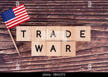Handelskriegskonzept mit Blockbuchstaben mit der Aufschrift "HANDELSKRIEG" und US-Flagge auf Holztisch, Symbol für globale wirtschaftliche Spannungen Stockfoto