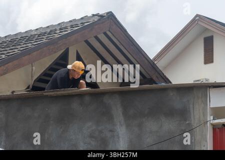 Jakarta, Indonesien - 9. Februar 2025: Ein Mann renoviert tagsüber das Dach eines Hauses Stockfoto