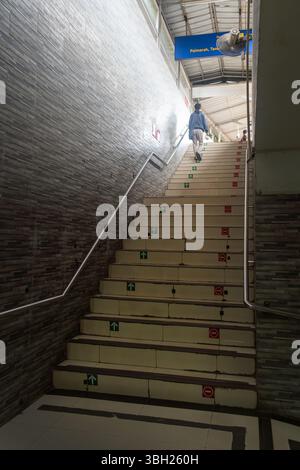 Jakarta, Indonesien - 9. Februar 2025: Eine Person geht eine Treppe in einem Gebäude hinauf. Die Treppen sind mit Pfeilen und Schildern markiert, und es gibt eine Stockfoto