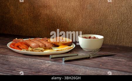 Ein Teller mit einem nahrhaften, herzhaften Frühstück auf einem Holztisch, Rührei, gebratenem Speck, Croutons, Würstchen, Tomaten und Pilze, eine geraffte Tasse Stockfoto