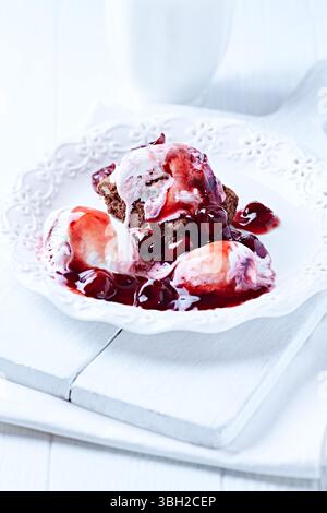 Erdbeereis mit Schokolade und Kirschsirup auf Schokoladenbrownie. Selektiver Fokus. Stockfoto