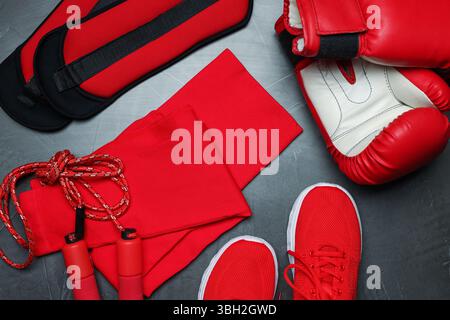 Sportbekleidung, Turnschuhe, Boxhandschuhe, Seilspringen und Knöchelgewichte auf grauem Hintergrund, flach Stockfoto