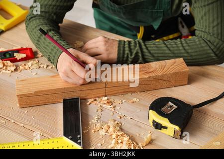 Zimmerfrau markiert Holzplanke mit Bleistift in der Werkstatt Stockfoto