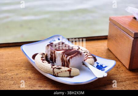 Nahaufnahme eines Gourmet-Bananendesserts mit dunkler Schokolade und coconat-Eis Stockfoto