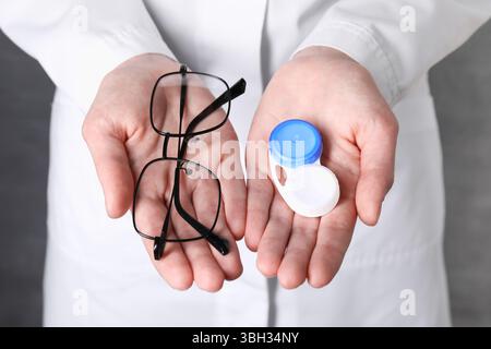 Arzthalter mit Kontaktlinsen und Brille auf grauem Hintergrund, Großaufnahme Stockfoto