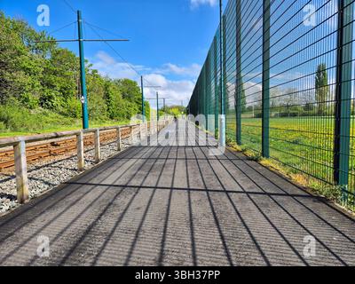Weg mit Zaunschatten, der neben dem Eisenbahngleis in Nottingham, England verläuft Stockfoto