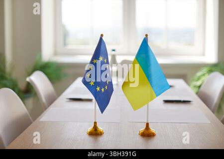 Flaggen der Europäischen Union und der Ukraine auf dem Tisch im Sitzungssaal symbolisieren internationale Verhandlungen Stockfoto