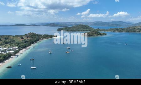 Aus der Vogelperspektive auf eine friedliche Bucht mit verankerten Yachten in der Nähe von Gili Asahan. Palmen gesäumte Ufer und smaragdgrüne Gewässer bieten eine traumhafte Inselatmosphäre. Stockfoto
