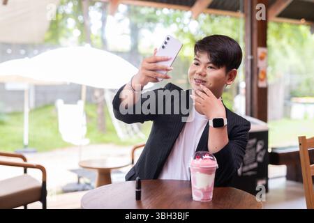 Junger süßer schwuler Mann Makeup Künstler Geschäftsmann im Café Restaurant mit Geschäftskleidung Stockfoto