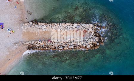 Blick von oben auf eine Mole am kroatischen Strand in der Stadt Makarska. Aus der Vogelperspektive auf die Küste und die blaue Adria Stockfoto