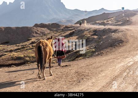 Eine einheimische Frau mit ihrem Pferd auf dem Weg zum Berg Vinicunca Rainbow, Peru Stockfoto