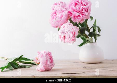 Rosafarbene Pfingstrosen in Keramikvase auf Holztisch. Stillleben. Stockfoto