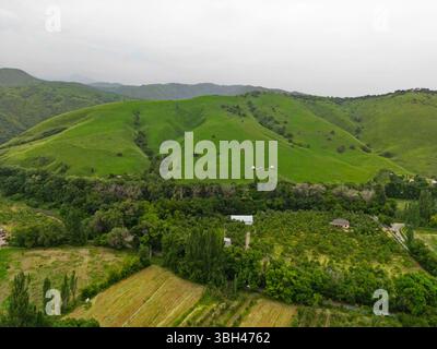 Ein Dorf am Stadtrand. Hügeliges Gelände mit unterschiedlicher Vegetation. Der Blick von der Drohne. Stockfoto