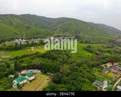 Ein Dorf am Stadtrand. Hügeliges Gelände mit unterschiedlicher Vegetation. Der Blick von der Drohne. Stockfoto