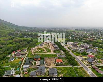 Ein Dorf am Stadtrand. Hügeliges Gelände mit unterschiedlicher Vegetation. Der Blick von der Drohne. Stockfoto