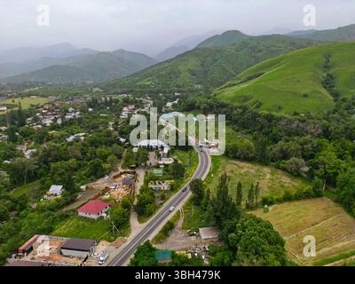 Ein Dorf am Stadtrand. Hügeliges Gelände mit unterschiedlicher Vegetation. Der Blick von der Drohne. Stockfoto
