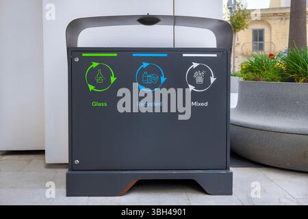 Moderner öffentlicher Recyclingbehälter mit drei beschrifteten Bereichen: Glas (grün), recycelbarer Abfall (blau) und gemischter Abfall (weiß). Stockfoto
