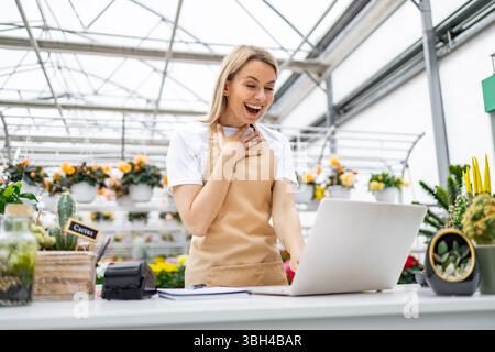 Happy Florist schaut auf Laptop Stockfoto