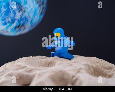 Tambow, Russische Föderation - 28. Juli 2024 Blaue Lego-Astronauten-Minifigur, die auf Sand auf einem Planeten vor schwarzem Weltraum mit einem weiteren Blau läuft Stockfoto