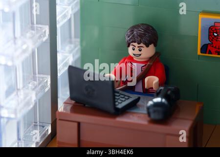 Tambow, Russische Föderation – 12. Februar 2025 Lego Peter Parker Minifigur arbeitet hinter einem Laptop an seinem Arbeitsplatz Stockfoto