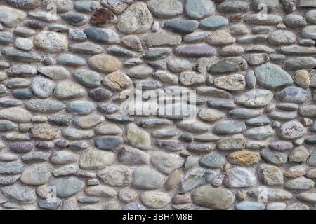 Wand mit bunten zementierten Kieselsteinen. Sie kann als Hintergrund verwendet werden Stockfoto